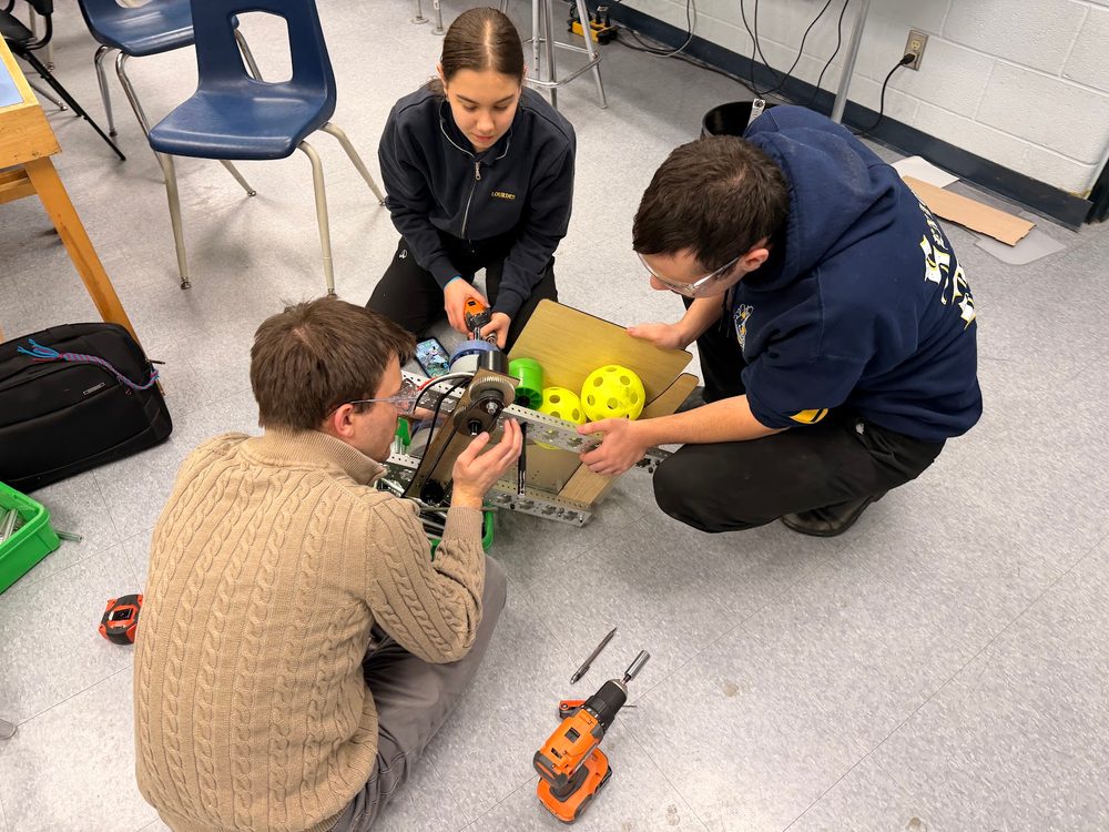 A mentor and students building a small FTC-scale robot