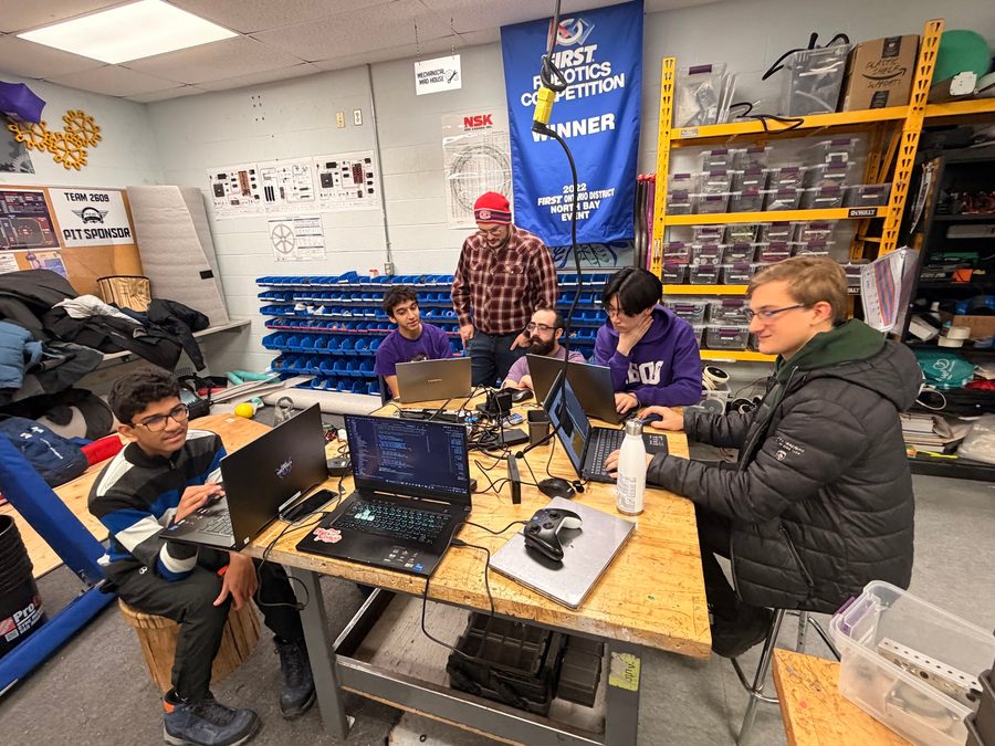 Students programming and testing a robot on laptops